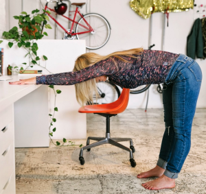 Women stretching hips & low back at desk