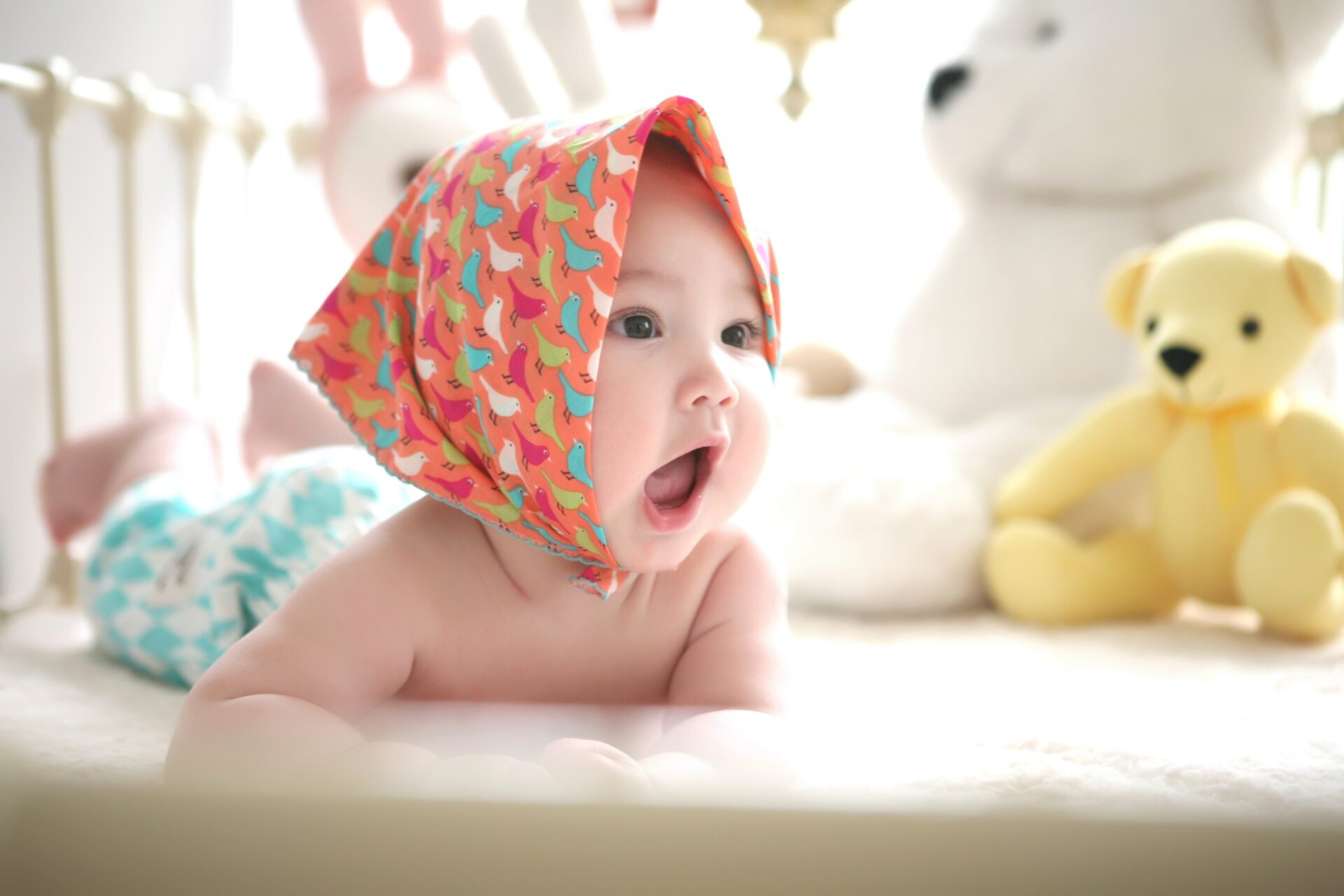 Baby with duck scarf lying on belly